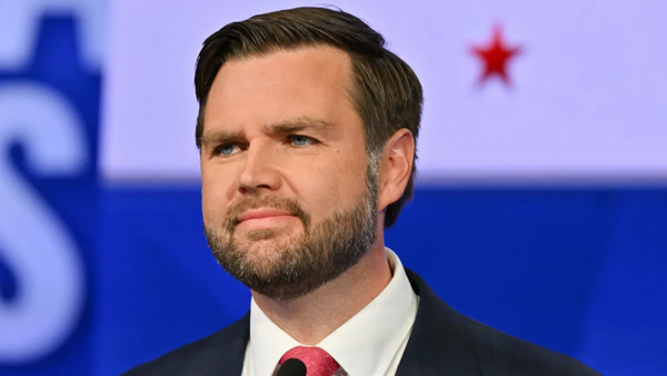 A white man wearing a black suit looks forward.